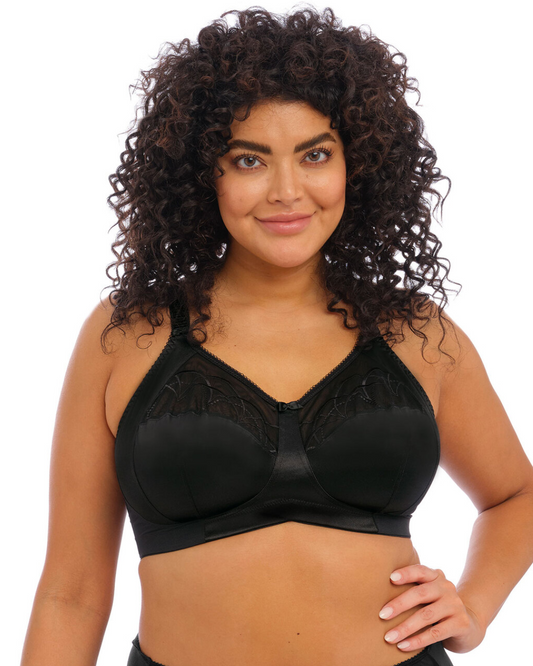 Elomi Cate Soft Cup Bra in black with sheer embroidery, soft satin cups, and an intersecting arc design. The bra offers three-piece cups with side support for shaping, uplift, and separation. It features a wide elastic underband, flexible side boning, and powernet wings for enhanced support. Complete with charming bow details, this bra combines elegance and comfort.