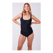 A model is wearing a solid black one-piece swimsuit with adjustable straps, designed to accommodate an ostomy bag.