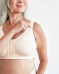 A woman wearing the cancer research post surgery mastectomy recovery bra in blush featuring a seamless design with wide, adjustable straps and a front hook and eye fastening.