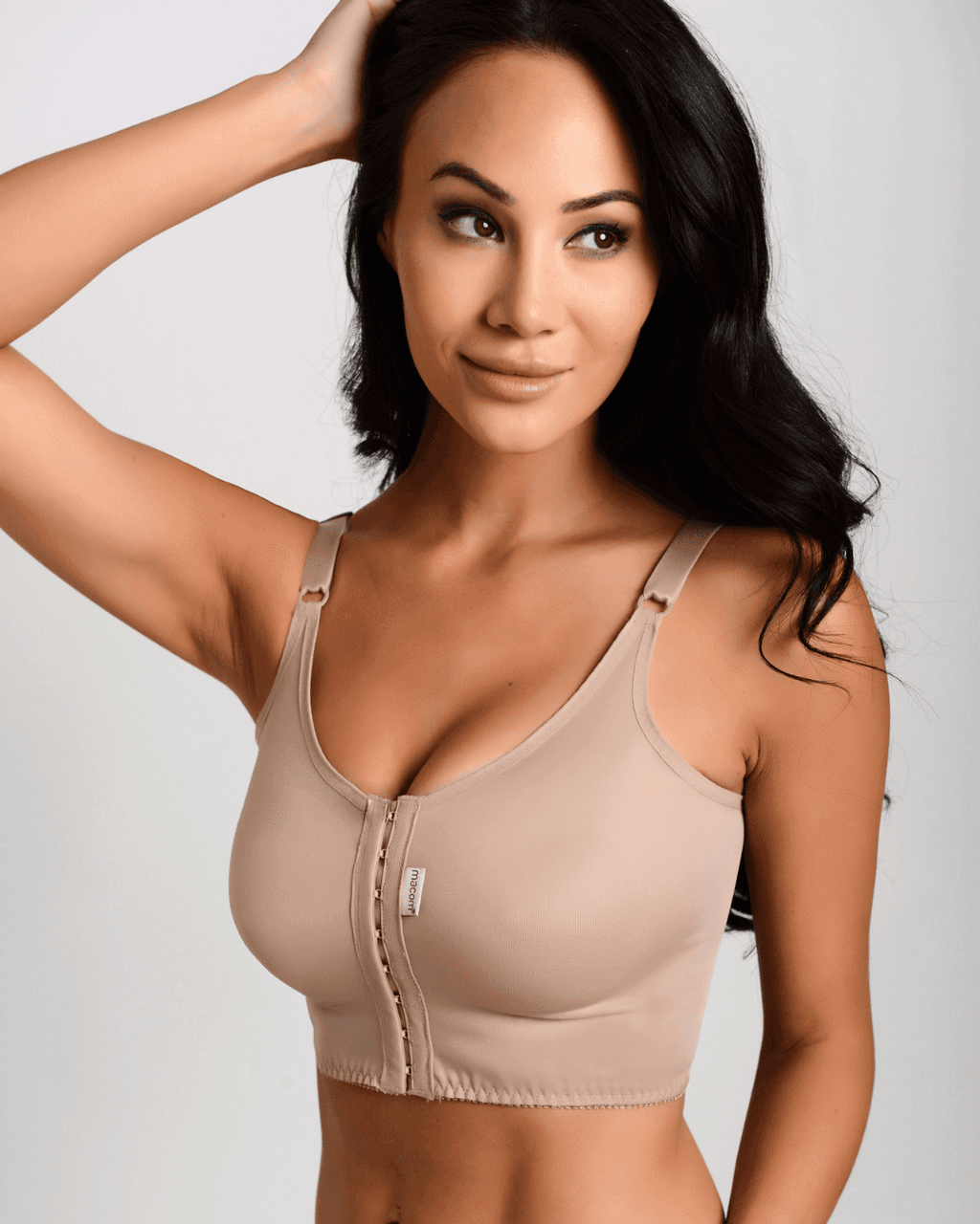 Woman wearing the Macom Signature bra in Clay. The Signature bra is suitable to be worn after most breast surgeries including augmentation and reduction. It features a hook and eye front fastening and thin adjustable straps for wardrobe versatility.